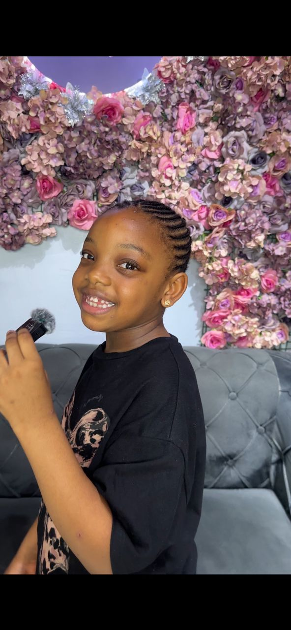 A child having her hair braided during camp